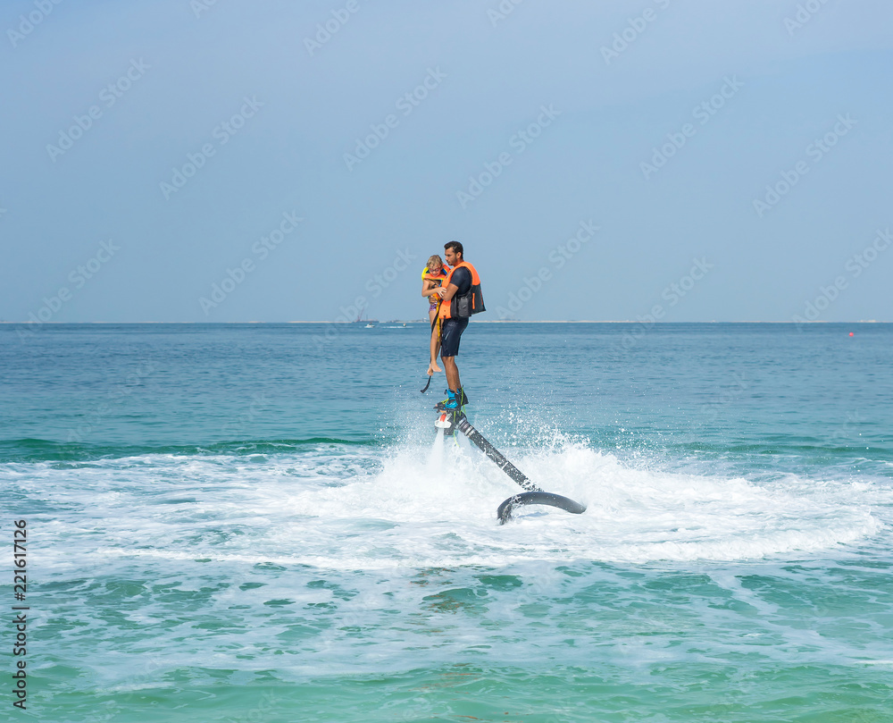 Father and his daughter posing at new flyboard at Caribbean tropical beach. Positive human emotions, feelings, joy. Funny cute child making vacations and enjoying summer.