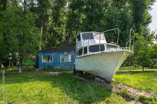 Old sailing yacht on land. Old white motor yacht beached at a dock for painting and repair. Powerboat beached for annual service and repair
