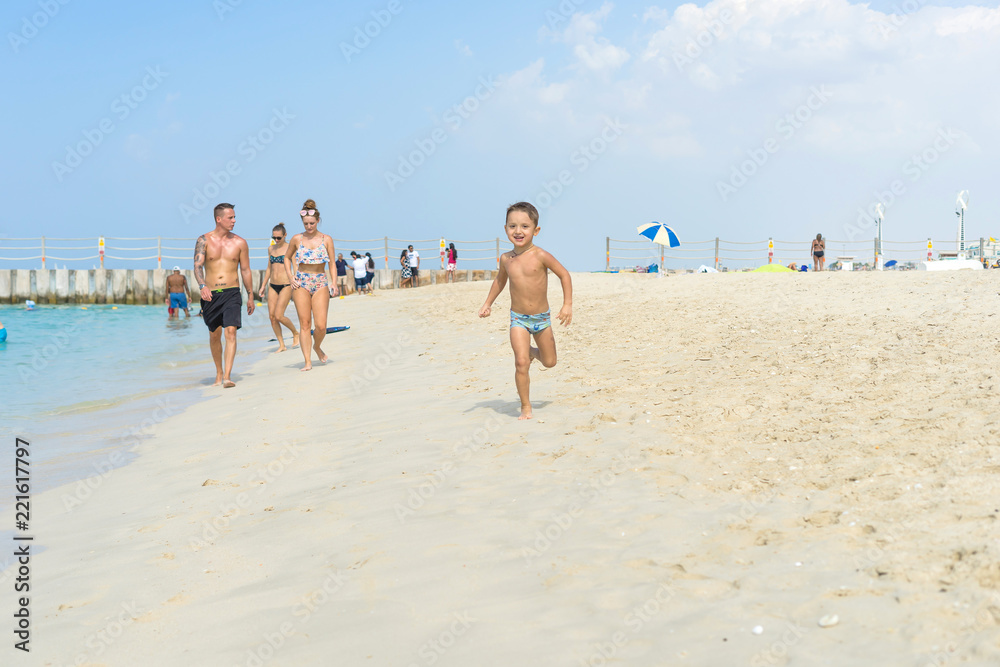 Happy little boy running on sand tropical beach. Positive human emotions, feelings, joy. Funny cute child making vacations and enjoying summer.