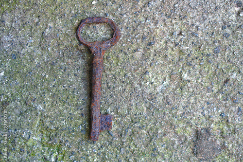 An antique rusty metal key on the background of concrete. A romantic secret protected by mystery. Stock photo. © subjob