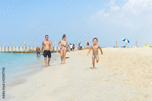 Happy little boy running on sand tropical beach. Positive human emotions, feelings, joy. Funny cute child making vacations and enjoying summer.