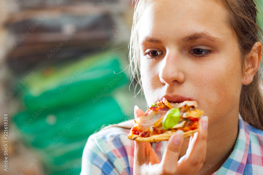 portrait of young teenager brunette girl eating a slice of pizza
