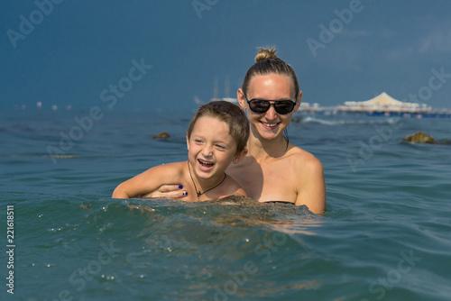 Happy child on sea with mom, family vacation, holiday in ocean. Last minute tours for summer. Summer vacation in water, happy family, mother with baby boy kid. Parent teaches funny child to swim © Evgenia