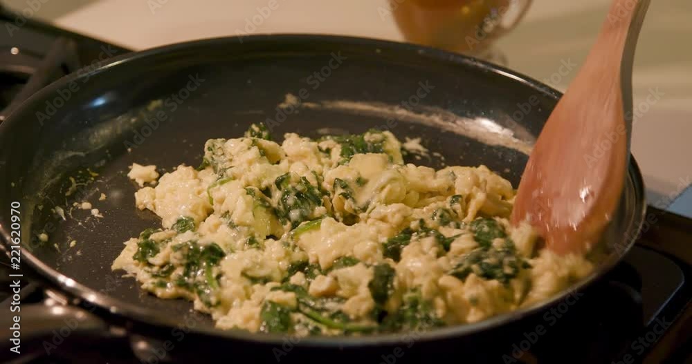 Nutritious and versatile suitable for any time of the day scrambled eggs enhanced with leafy green spinach being gently stirred in a non-stick skillet. Slow motion 4k footage. Nutritious and versatile suitable for any time of the day scrambled eggs enhanced with leafy green spinach being gently stirred in a non-stick skillet. Slow motion 4k footage.