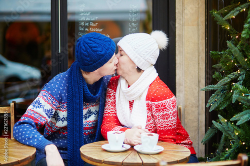 Couple drinking coffee in cafe decorated for Christmas