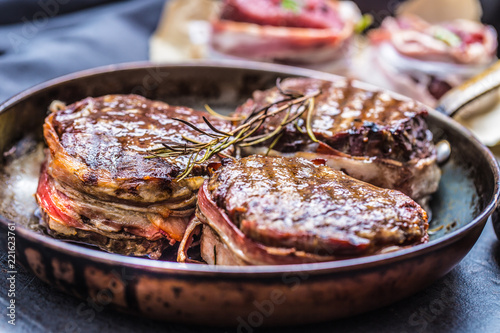 Foto Three grilled beef tenderloin steaks coated bacon on a frying pan