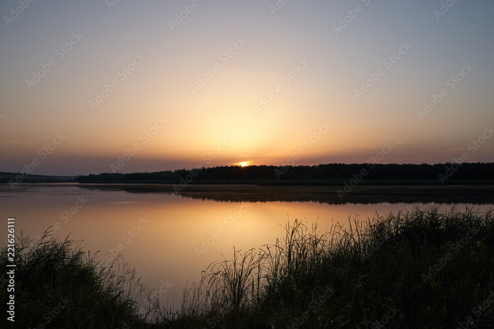 Dawn landscape of the lake with warm gentle tones in the reflection of the surface of the water