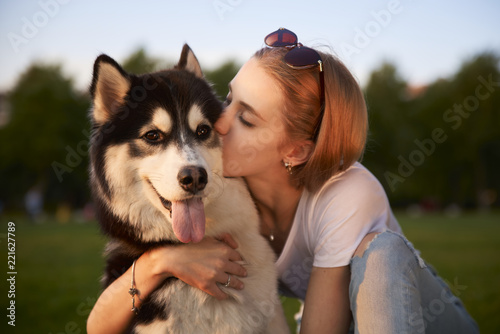 A young girl while walking in the Park with a dog hugs the dog Laika and kisses. Casual clothes, jeans and a white t-shirt