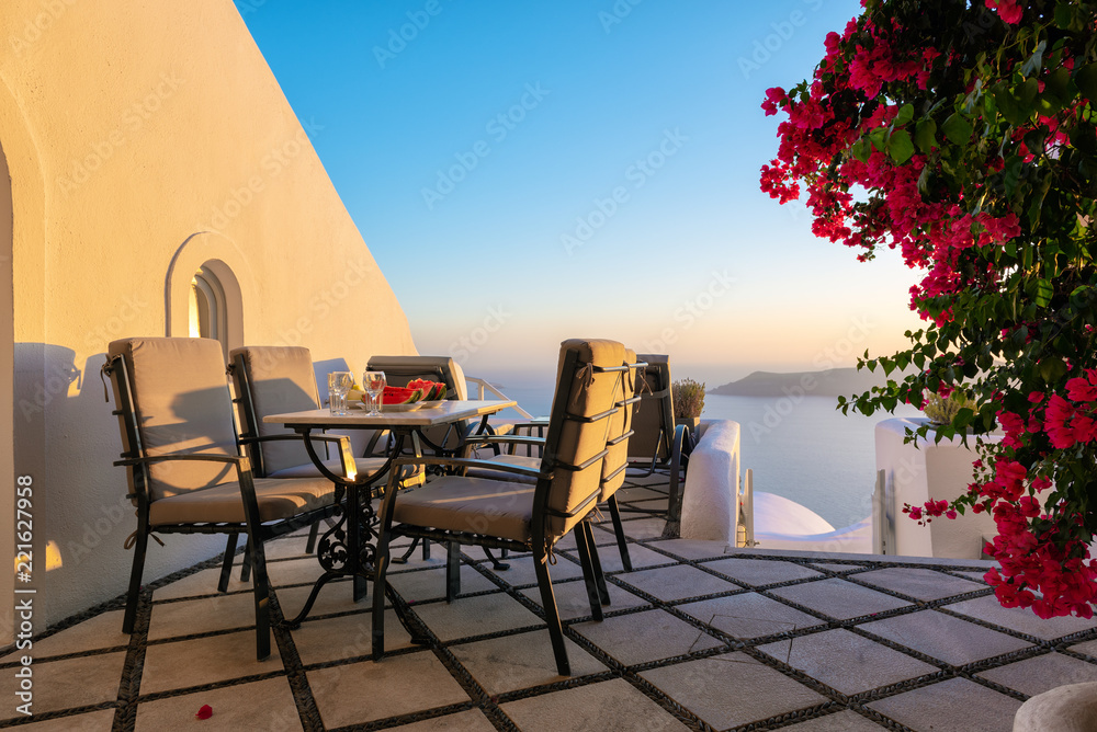 Patio with table and chairs decorated with beautiful bougainvillea flowers at Santorini island, Greece
