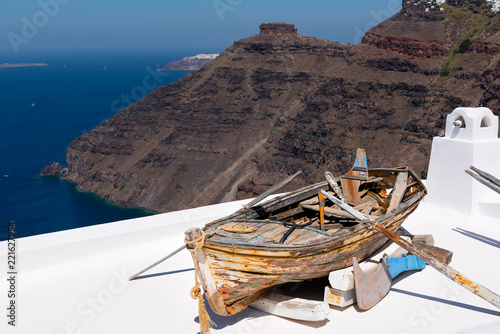 Old wooden broken boat on roof of house, located at Santorini island, Greece photo
