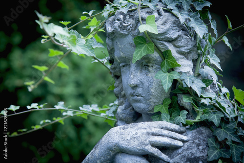 Antique sculpture of an angel with ivy against  dark background