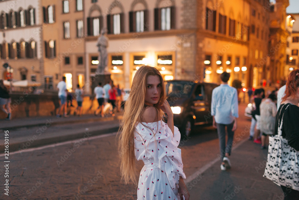 Beautiful girl walks through the evening city