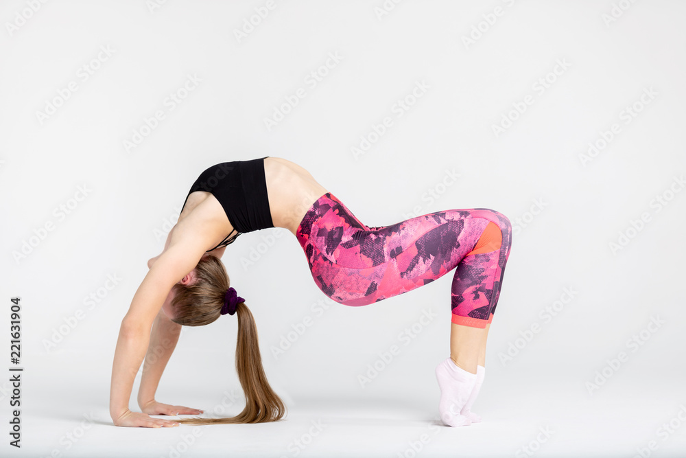 Young sportwoman stretching muscles on white background