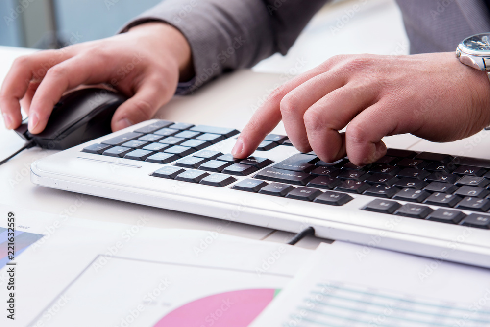 Finance professional working on keyboard with reports Finance professional working on keyboard with reports