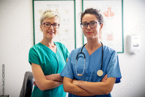 Portrait of two professional nurses standing in their office in front of a camera. photo