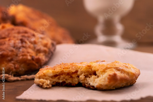 Broken round home-made cookies on a paper napkin, wooden background, close-up.