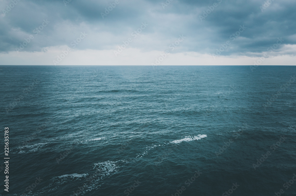 Dramatic stormy dark cloudy sky over sea, natural photo background