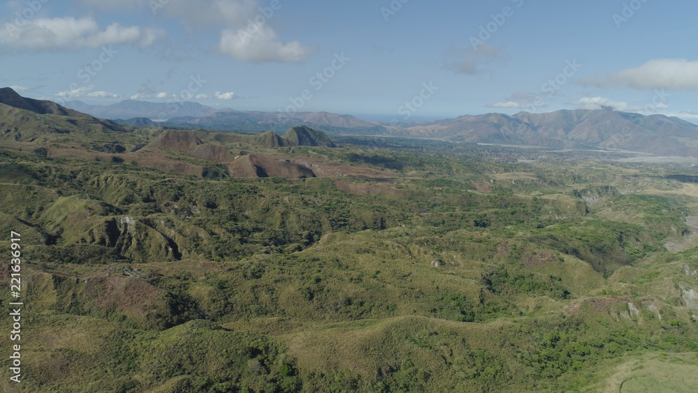 Aerial view of mountains covered with green vegetation, valley, trees in vicinity volcano Pinatubo. Slopes of mountains, sky and clouds. Cordillera region. Luzon, Philippines.