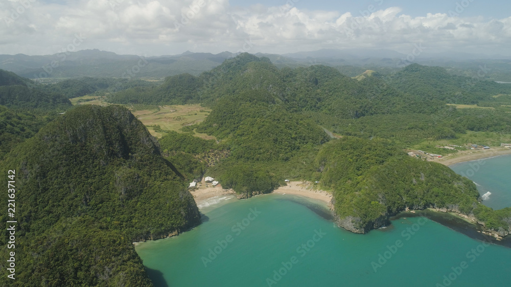 Aerial view of islands with sand beach and turquoise water in blue lagoon among coral reefs, Caramoan Islands, Philippines. Mountains covered with tropical forest.