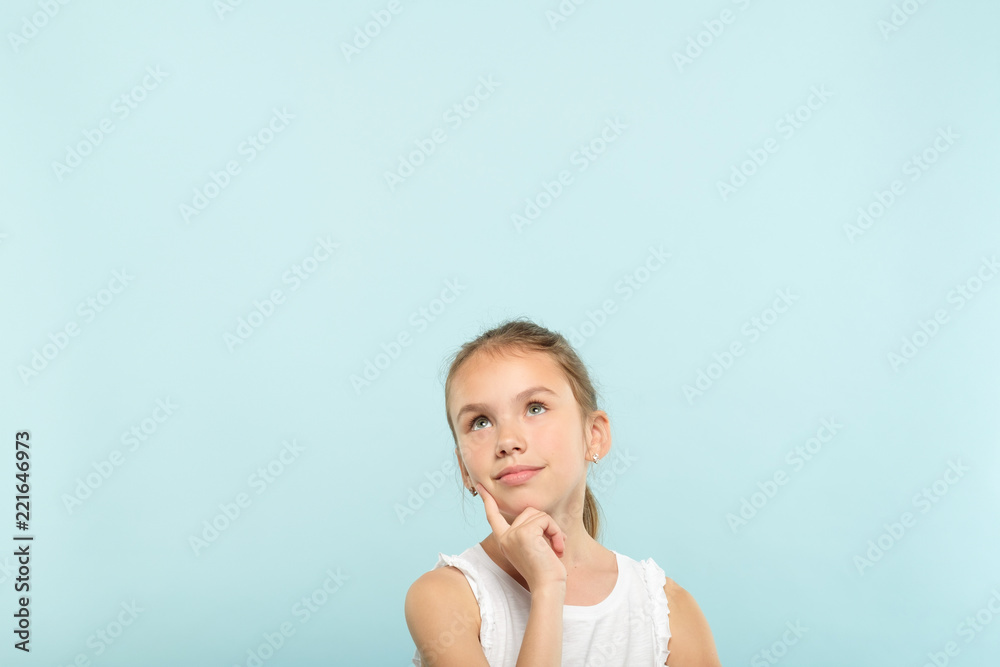 smiling pretty dreamy young girl looking up at a virtual object or text speech bubble. empty space for advertising. portrait of a cute child on blue background. smiling pretty dreamy young girl looking up at a virtual object or text speech bubble. empty space for advertising. portrait of a cute child on blue background.