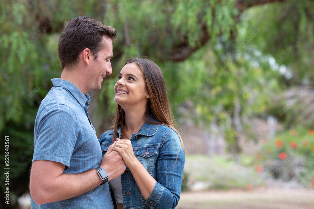 Fototapeta premium Beautiful young couple in love holding hands looking at each other with a smile.jpg