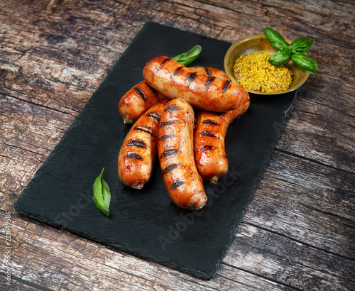 grilled sausages on a black slate on a wooden background