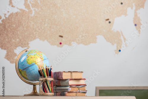 School background, books, globe and color pencils are on the desk