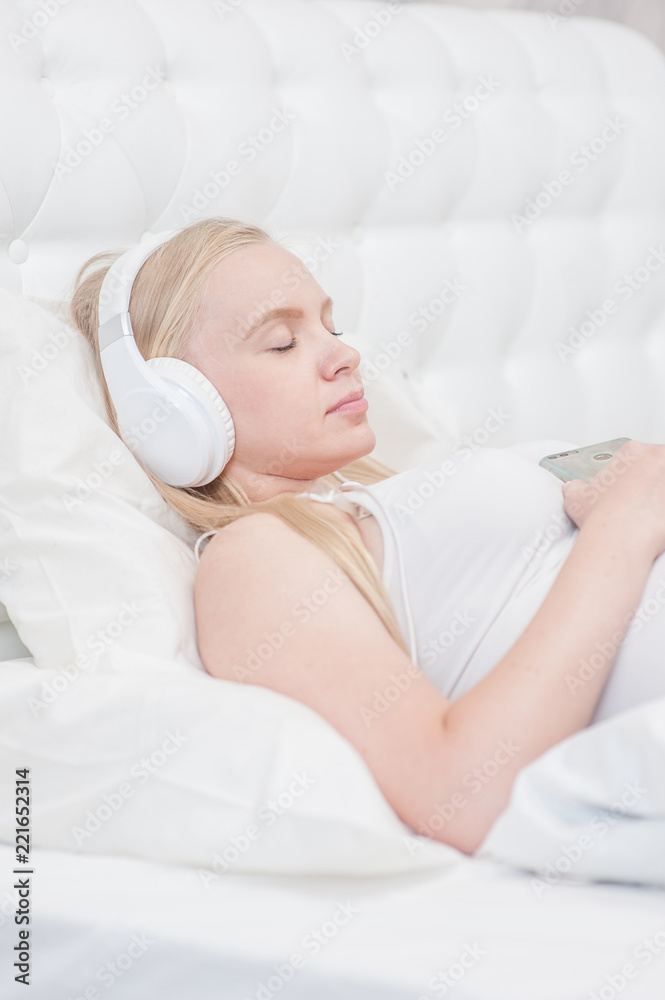 pregnant woman lying on bed at home and listening music in headphones pregnant woman lying on bed at home and listening music in headphones