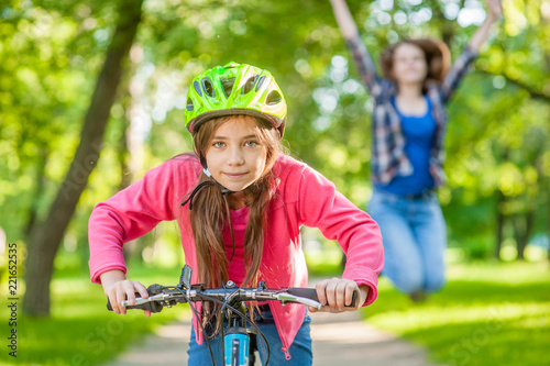 happy mother rejoices that her daughter learned to ride a bike