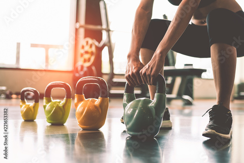 Close up of woman lifting kettlebell like dumbbells in fitness sport club gym training center with sport equipment near window background. Lifestyles and workout exercise for bodybuilding and healthy photo