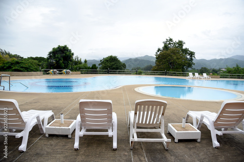 The outdoor swimming pool is in a natural setting with a mountain backdrop. © santipong