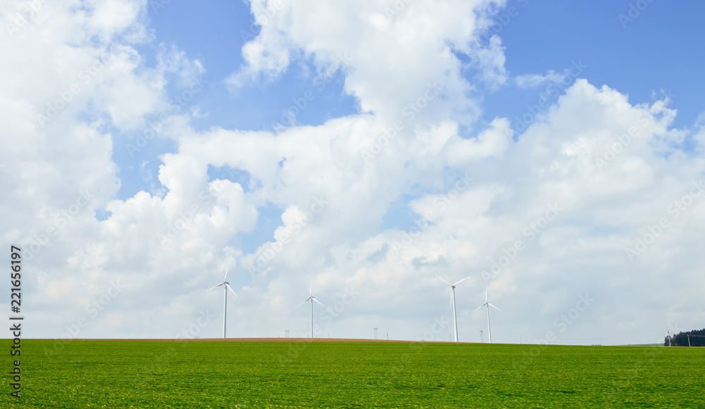 wind power mills standing on green meadow with clean background of blue sky and clouds wind power mills standing on green meadow with clean background of blue sky and clouds