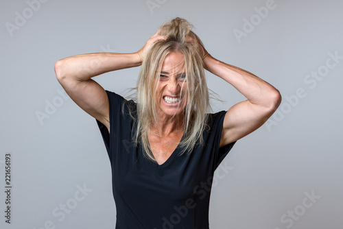 Frustrated woman tearing at her long blond hair