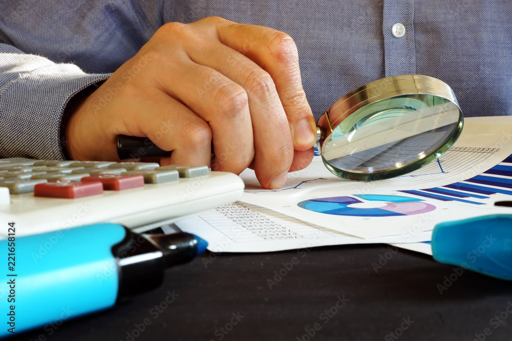 Accountant checking financial report with magnifying glass. Accounting.