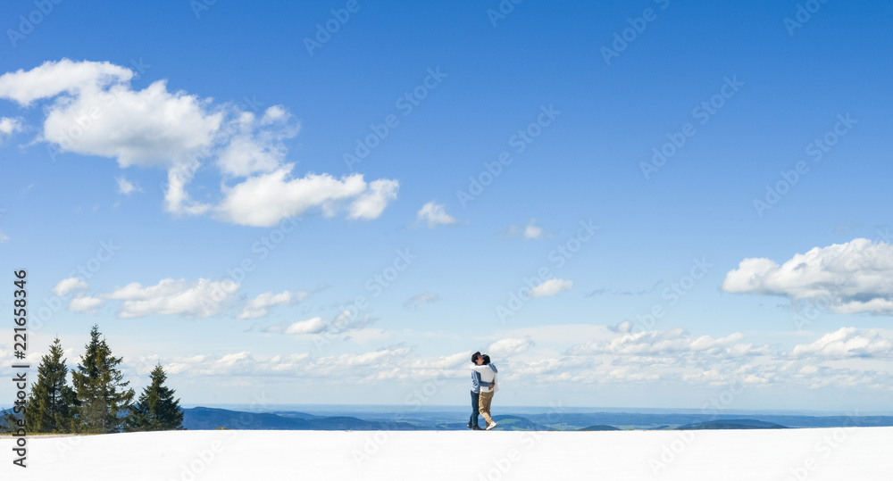 Young Asian couple hold each other, standing on snow at edge of Schafberg mountain (the mountain in movie 'sound of music'), Austria Young Asian couple hold each other, standing on snow at edge of Schafberg mountain (the mountain in movie 'sound of music'), Austria