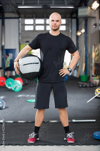 Determined Male Athlete Holding Medicine Ball In Health Club