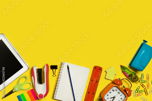 multiple school suplies and gadgets lying on a yellow surface. free space for advertising text photo