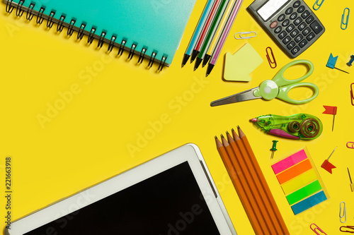various school and office suplies and gadgets lying on a yellow background. free space for text