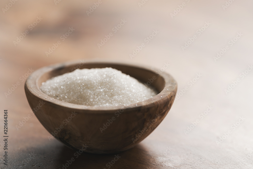 White sugar in wood bowl on table
