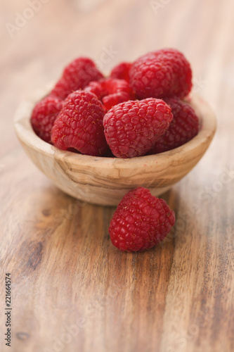 fresh raspberries in wood bowl on table with copy space