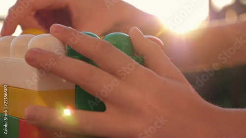 Wallpaper Mural Close-up of the boy's hand collecting the developing designer of the blocks sitting at the table in the rays of the setting sun. The concept of a happy childhood Torontodigital.ca