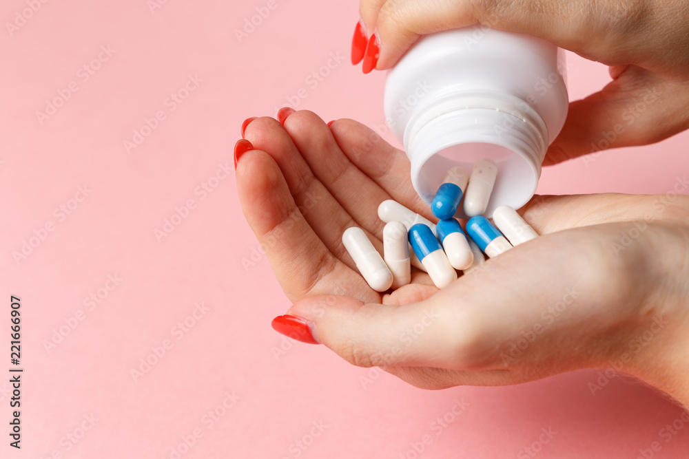 Woman holding pills on hand. Medicine and health care concept. Hand spilling pills for the pain of a bottle on pink background. Woman taking medicine. Healthy lifestyle, nutritional supplements Woman holding pills on hand. Medicine and health care concept. Hand spilling pills for the pain of a bottle on pink background. Woman taking medicine. Healthy lifestyle, nutritional supplements