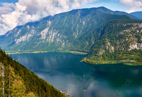 View of the city and Lake Hallstatt in Austria, the Alps mountains under a blue sky with clouds and forest in the background on a sunny day
