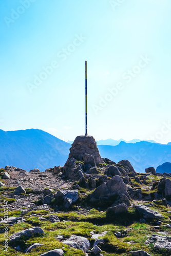 High alpine mountain top flagpole, summertime landscape. Reaching top of the hill concept.