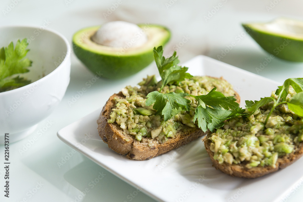 sandwiches with avocado and parsley on a plate, healthy food, chopped avocado on a piece of bread sandwiches with avocado and parsley on a plate, healthy food, chopped avocado on a piece of bread