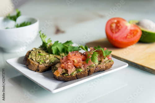 sandwiches with avocado and tomato on a plate, chopped avocado and tomatoes on slices of bread
