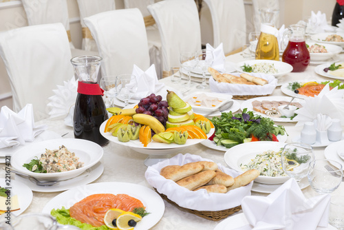 festive table, dishes on plates on the table with a tablecloth, plates, Cutlery, glasses, plate with fridges, snacks, salads, fish, jugs with drinks, vegetables on the table, Banquet table,