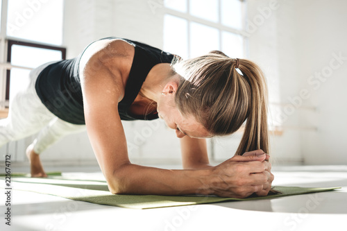 Healthy woman fitness doing exercise on abs in white sunny gum. Fit woman doing  crossfit workout on mat photo