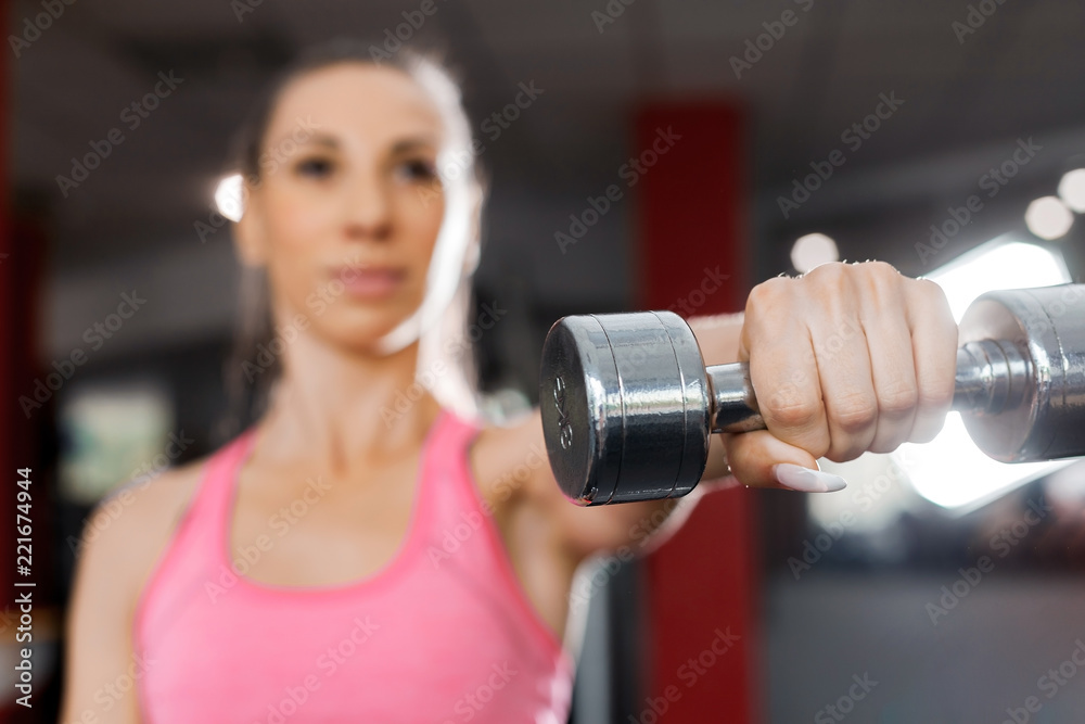 strong beauty fitness girl wearing pink and black professional sportswear holding a dumbbell in a gym close up. healthy lifestyle concept strong beauty fitness girl wearing pink and black professional sportswear holding a dumbbell in a gym close up. healthy lifestyle concept