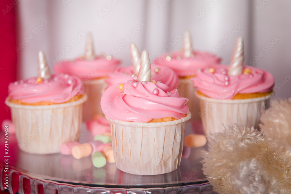 First baby girl birthday party concept. Candy bar with sweet unicorn cakes and decor items in bright pink colors. First baby girl birthday party concept. Candy bar with sweet unicorn cakes and decor items in bright pink colors.